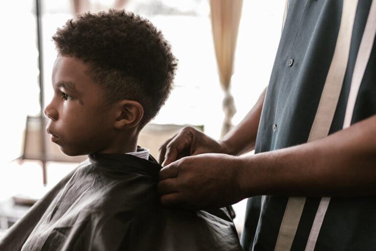 Young child sitting in a barber chair receiving a haircut